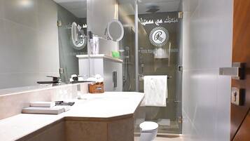 A modern bathroom with a large mirror, a sink, a toilet, and a shower area.