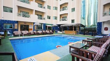 A hotel pool area with lounge chairs, umbrellas, and a bar.