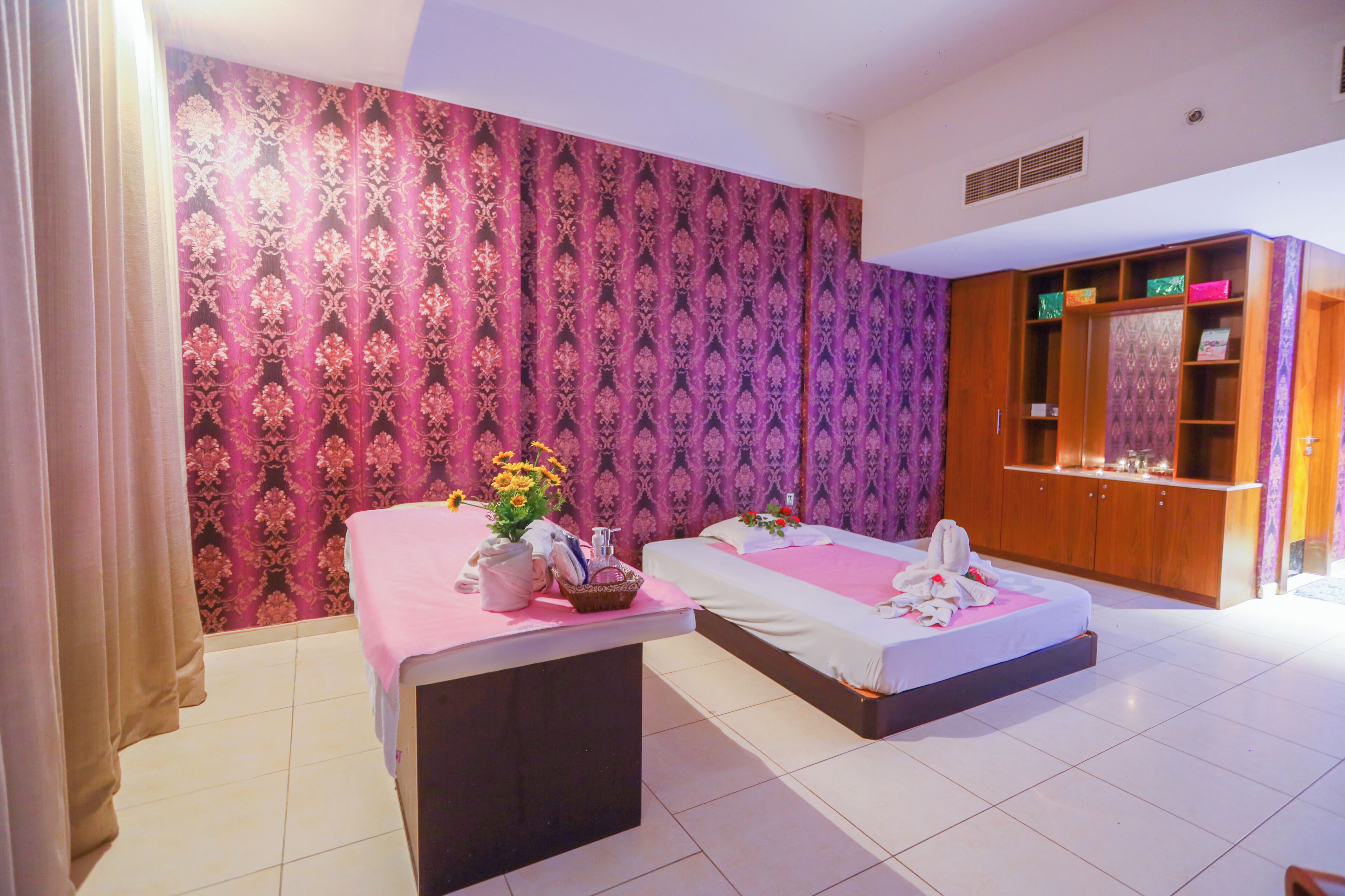 A hotel room with two beds, a vanity with a mirror, and a wardrobe.