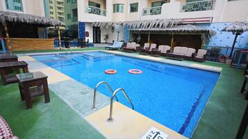 Uma piscina com trampolim, cadeiras de descanso e placa de salva-vidas.
