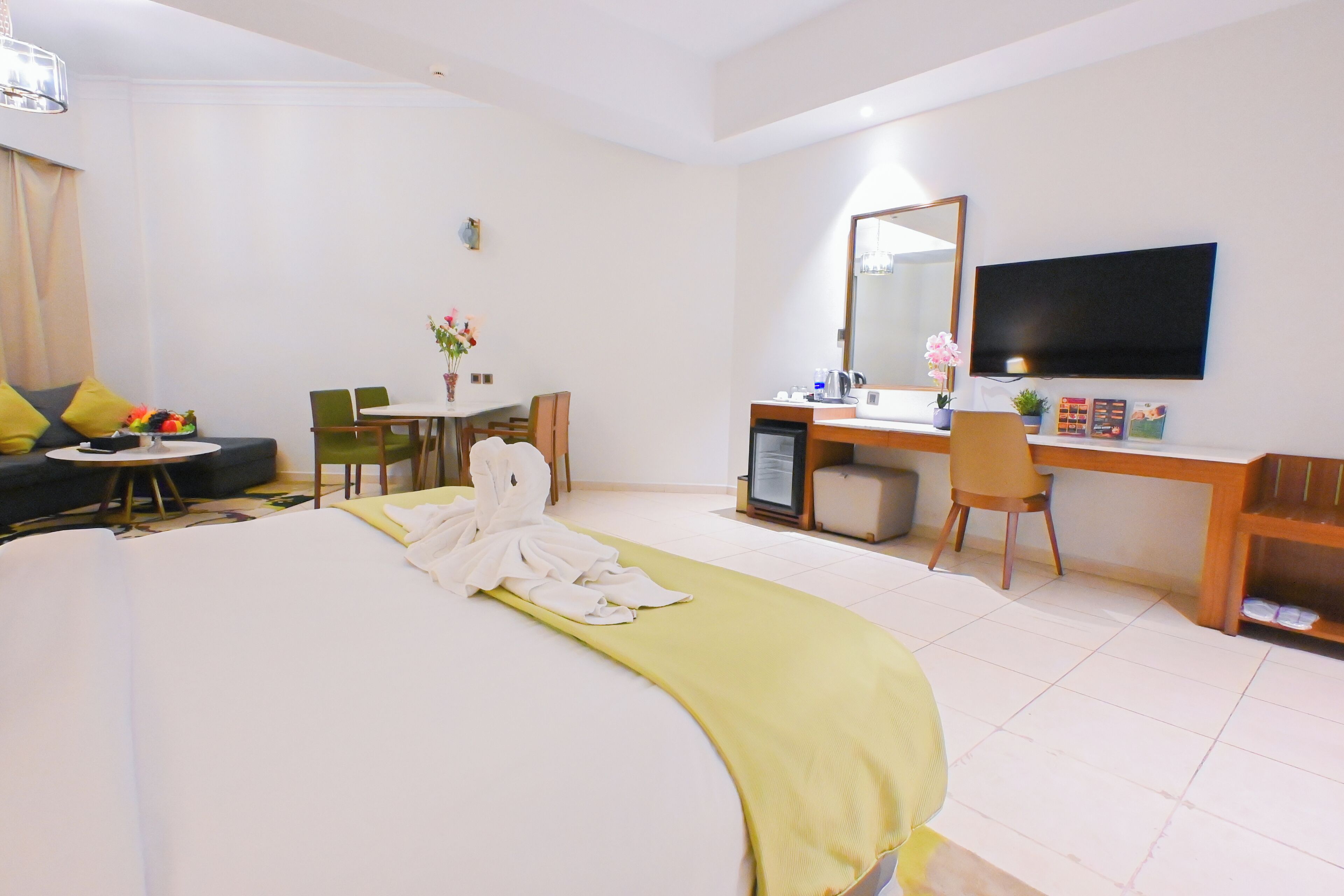 Een hotelkamer met een bed, een bureau, een stoel, een televisie en een tafeltje met bloemen.