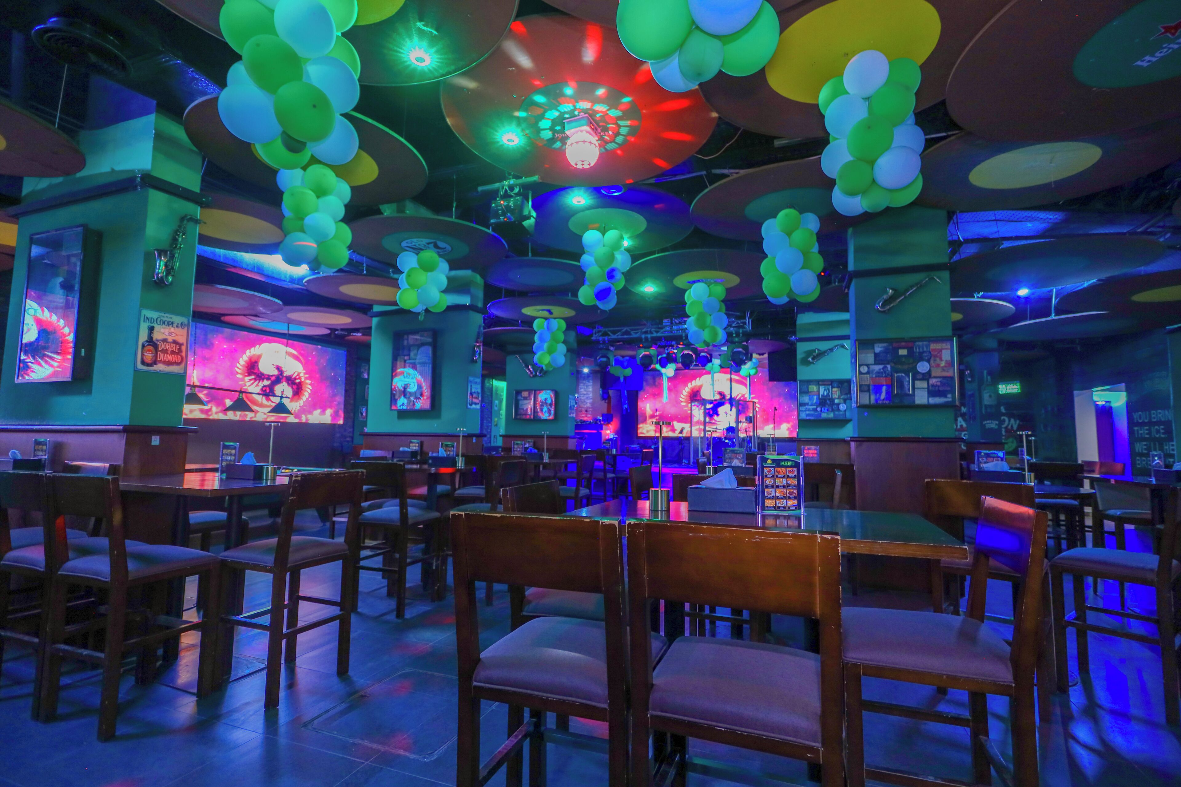 A restaurant with booths and tables, decorated with balloons and neon lights.