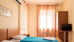 A hotel room with two beds, a TV, and a wardrobe. - Stefanakis Hotel & Apartaments (Vari-Voula-Vouliagmeni)
