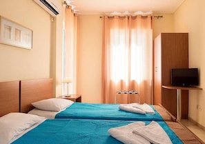 A hotel room with two beds, a TV, and a wardrobe. - Stefanakis Hotel & Apartaments (Vari-Voula-Vouliagmeni)