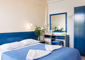 A hotel room with a bed, a nightstand, a mirror, and a blue headboard. - Stefanakis Hotel & Apartaments (Vari-Voula-Vouliagmeni)