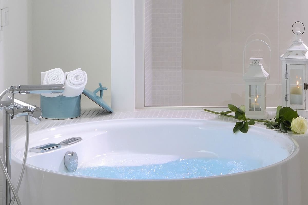 A bathroom with a bathtub, a towel rack, and a flower arrangement.