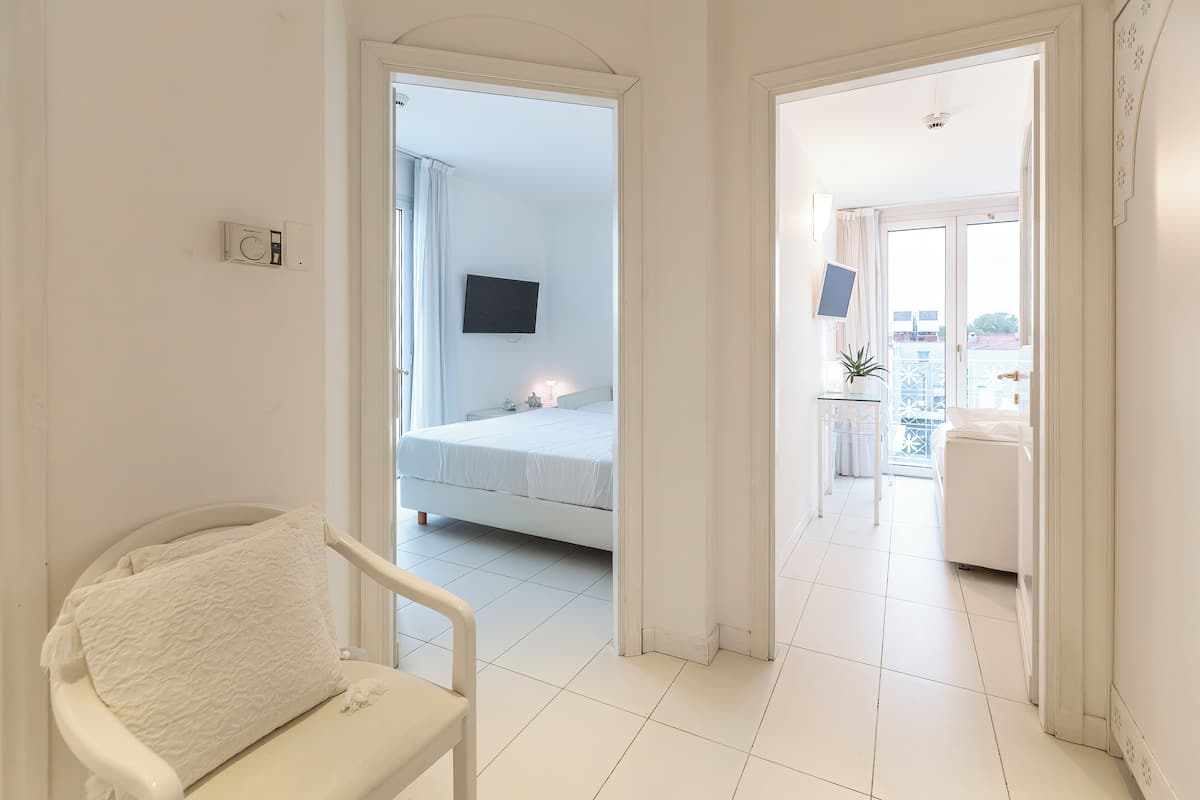 A hotel room with a bed, a chair, a TV, and a balcony with a view.