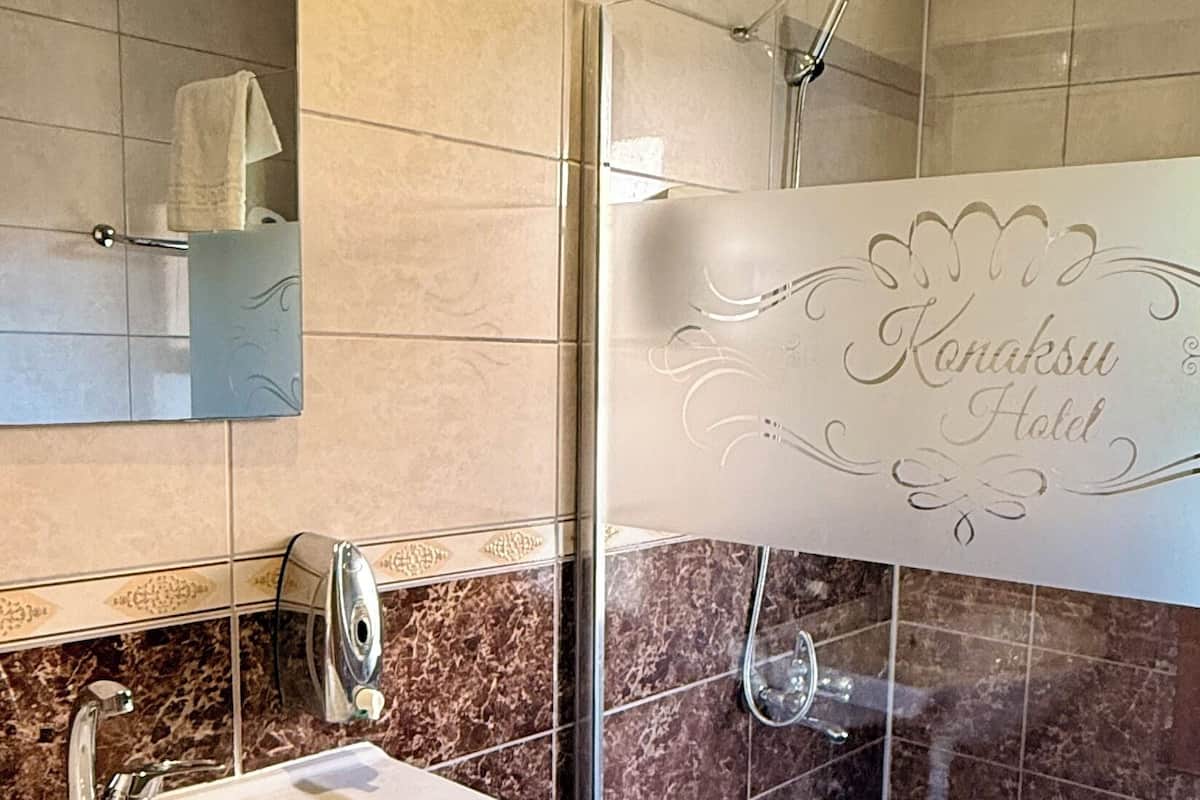 A bathroom with a sink, mirror, and shower.