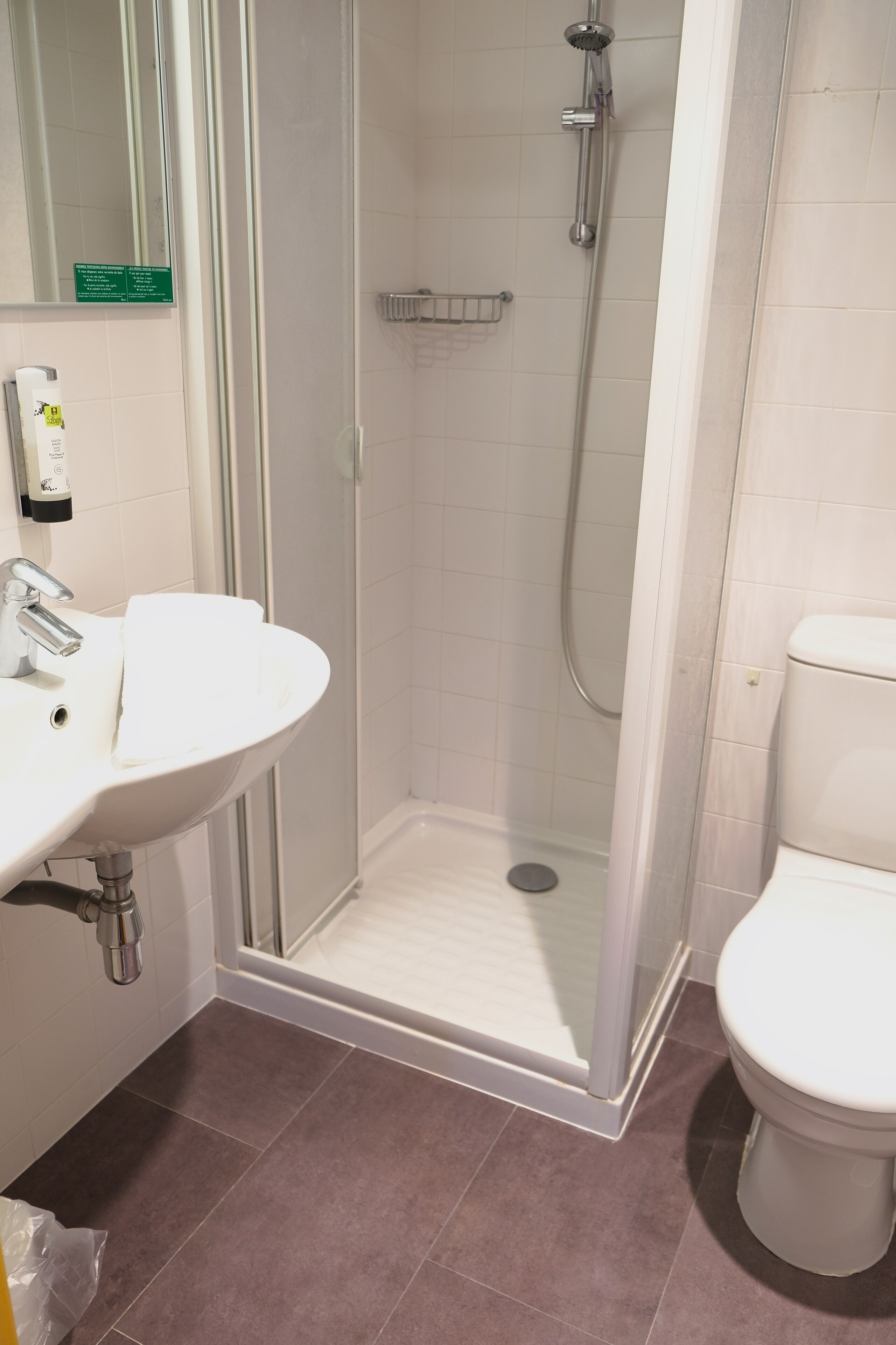 A bathroom with a shower, toilet, sink, and a glass-enclosed shower stall.