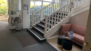 A staircase with white balusters leading to a second floor, a red couch, and a small table with a coffee machine. - Hotel Arcadia (Lannion)