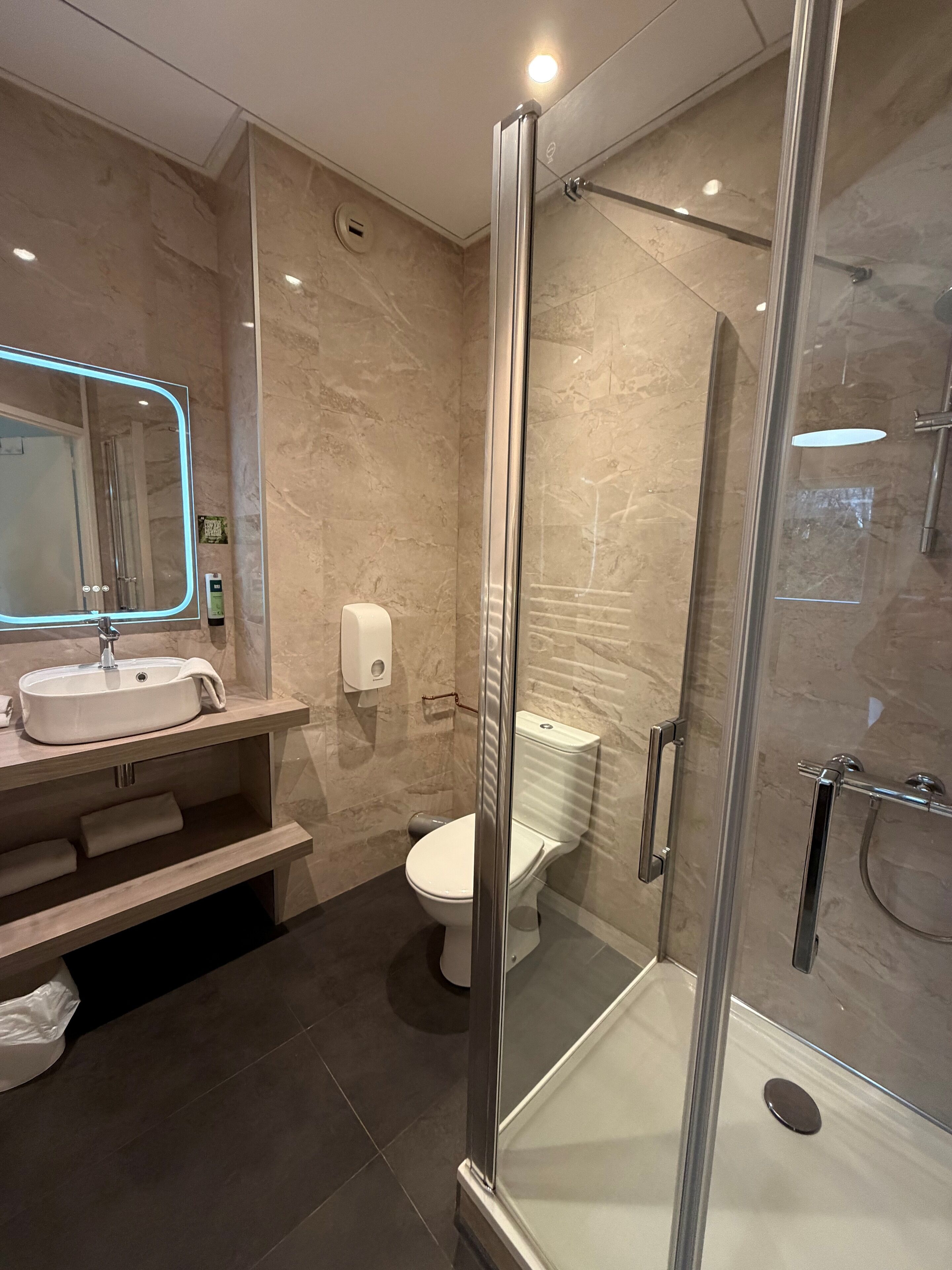 A modern bathroom with a glass-enclosed shower, a sink with a mirror, and a toilet.