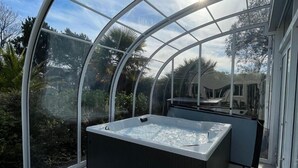 A glass-enclosed hot tub with a view of tropical vegetation. - Hotel Arcadia (Lannion)
