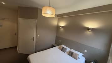 A hotel room with a bed, bedside tables, a hanging lamp, and wall-mounted lights.