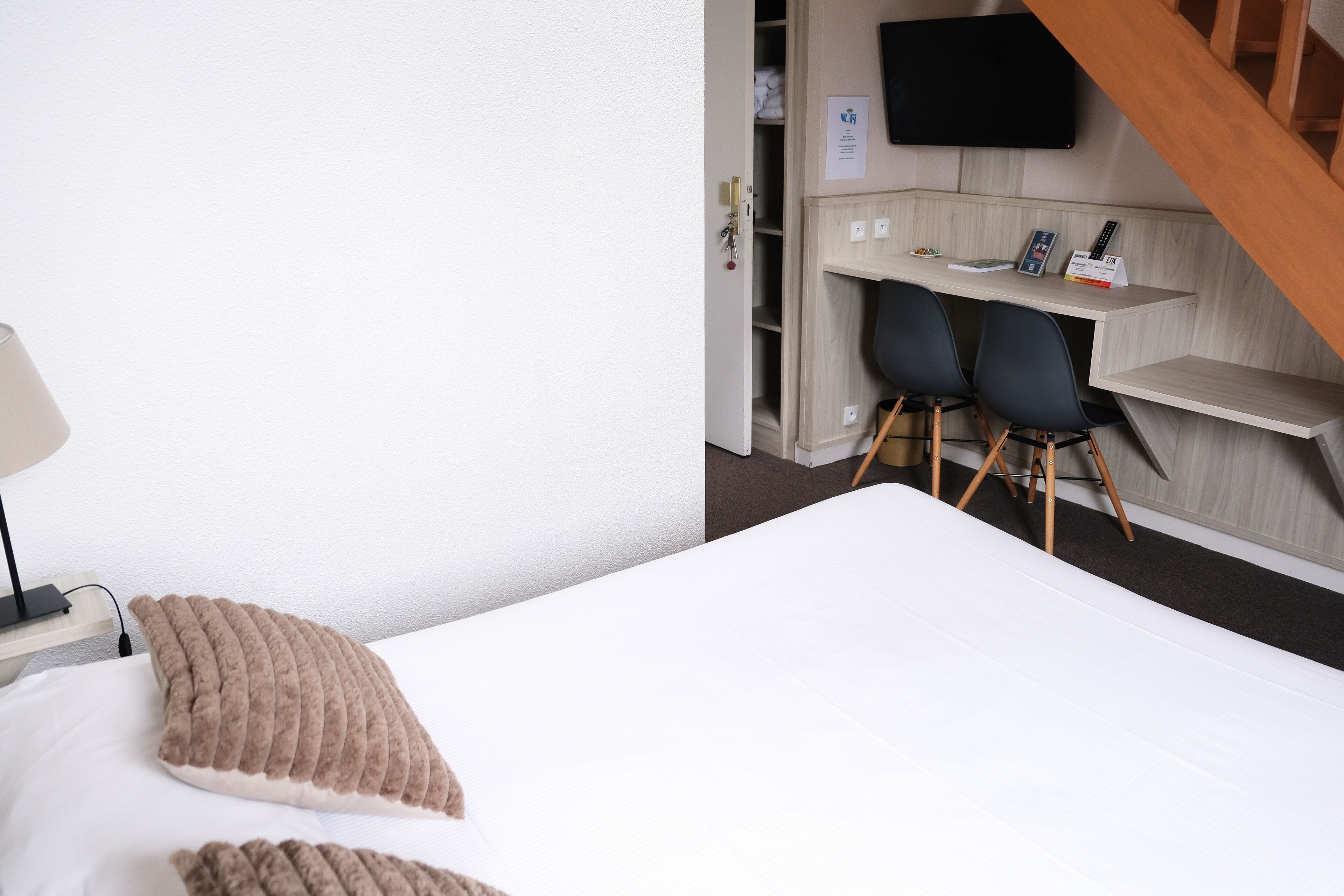 A hotel room with a bed, a desk, and a chair.