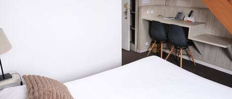 A hotel room with a bed, a desk, and a chair.