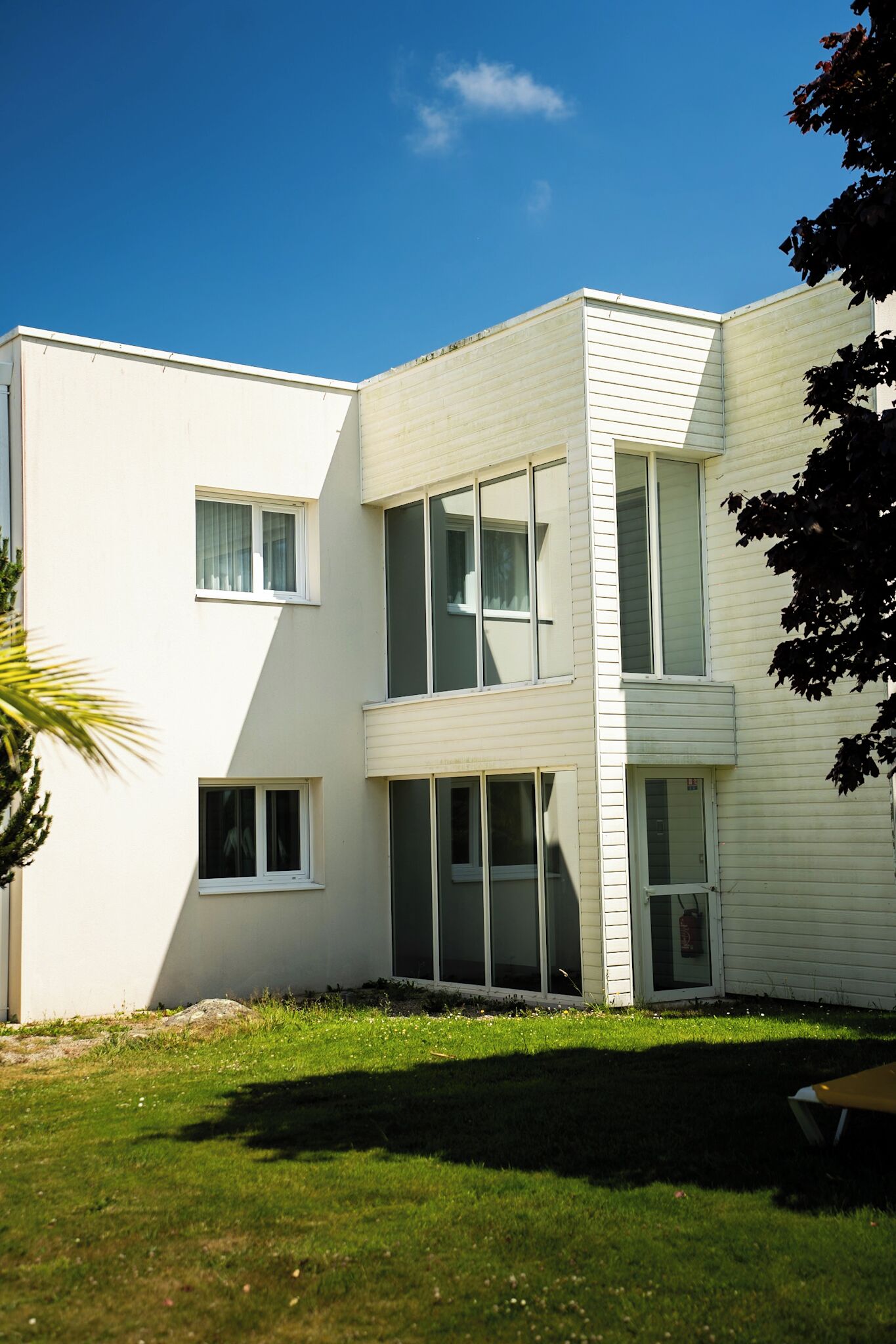 Un bâtiment moderne à deux étages, doté de grandes fenêtres et d’un toit plat.