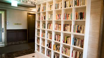 A library with white shelves filled with books, a chandelier, and a marble floor.