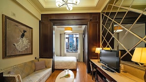 Habitación de hotel con cama, sofá, televisión y mesa de comedor con un florero.