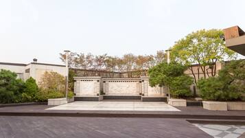 A courtyard with a wooden deck, stone benches, and a stone wall with carvings.