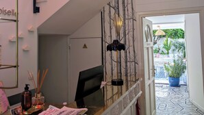 Un espace d’accueil d’hôtel comprenant un escalier, un bureau avec un ordinateur, une lampe fixée au mur et une vue sur le jardin extérieur.