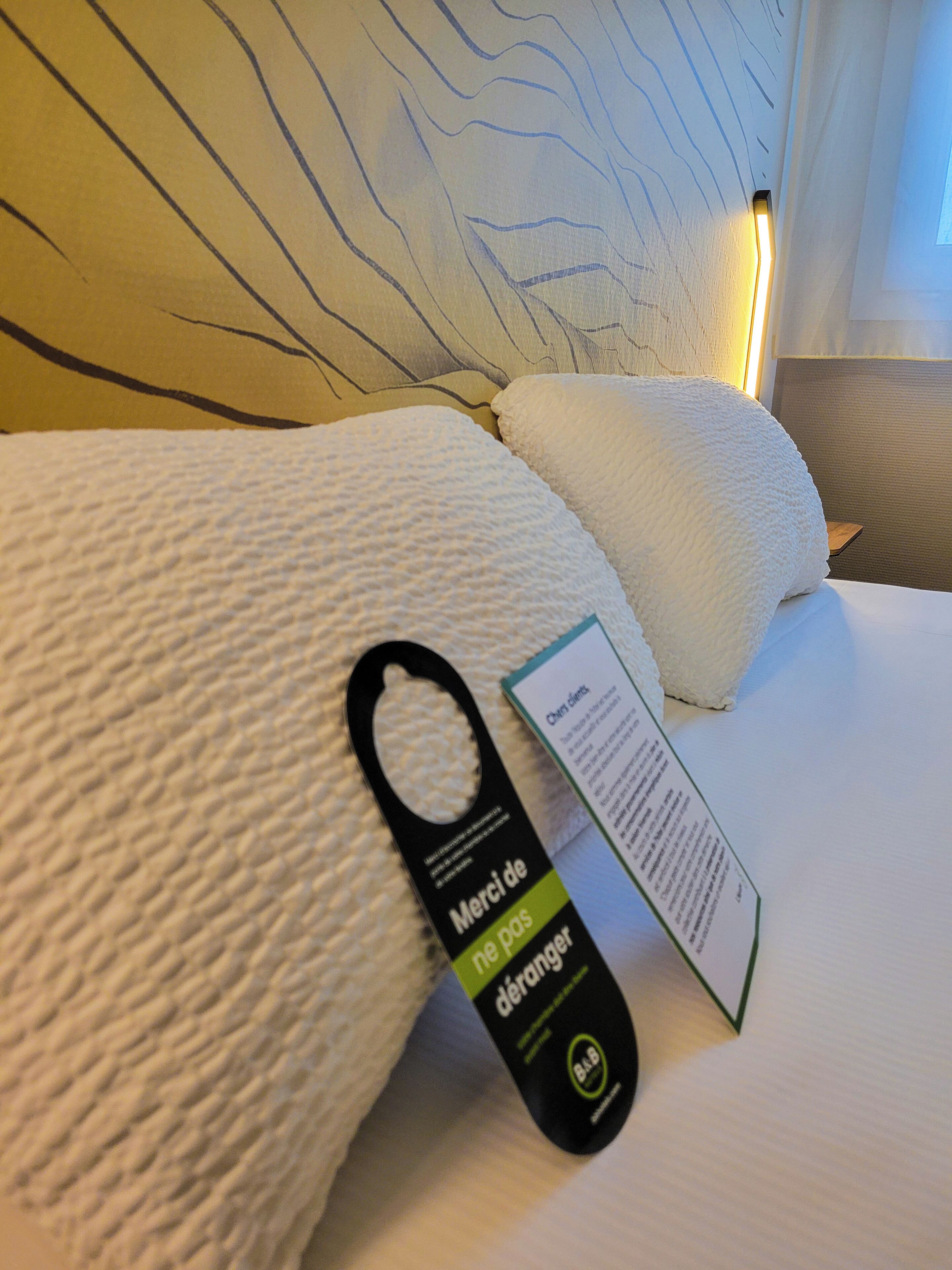 Una cama con almohadas blancas y una etiqueta negra con texto.
