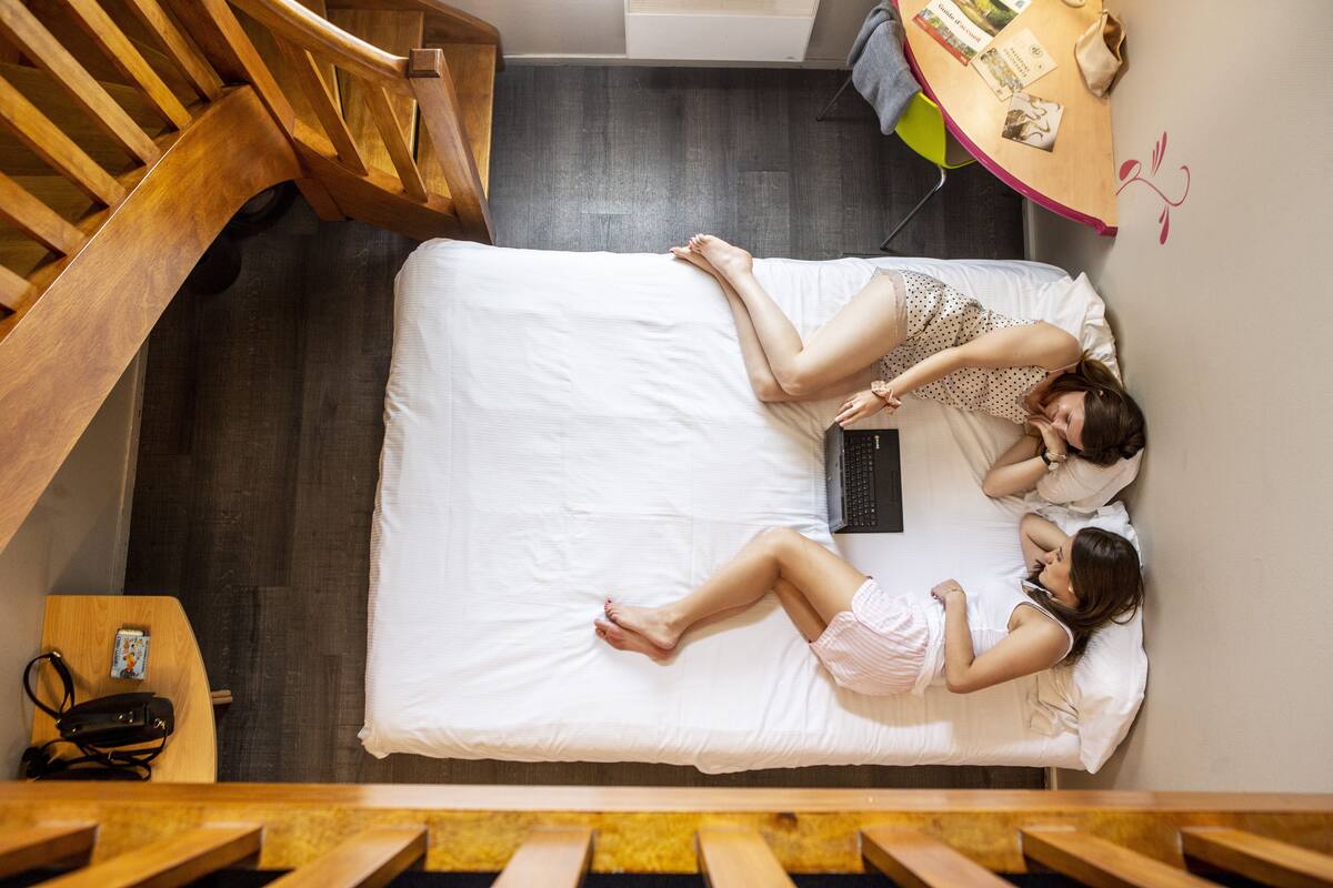 A bedroom with a bed, a wooden desk, and a staircase.