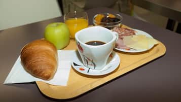 Bandeja de café da manhã com croissant, maçã, suco de laranja, xícara de café e um prato com queijo e salame.