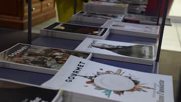 A table with stacks of magazines and books, including titles like 'Gourmet' and 'Dans La Cassette'.