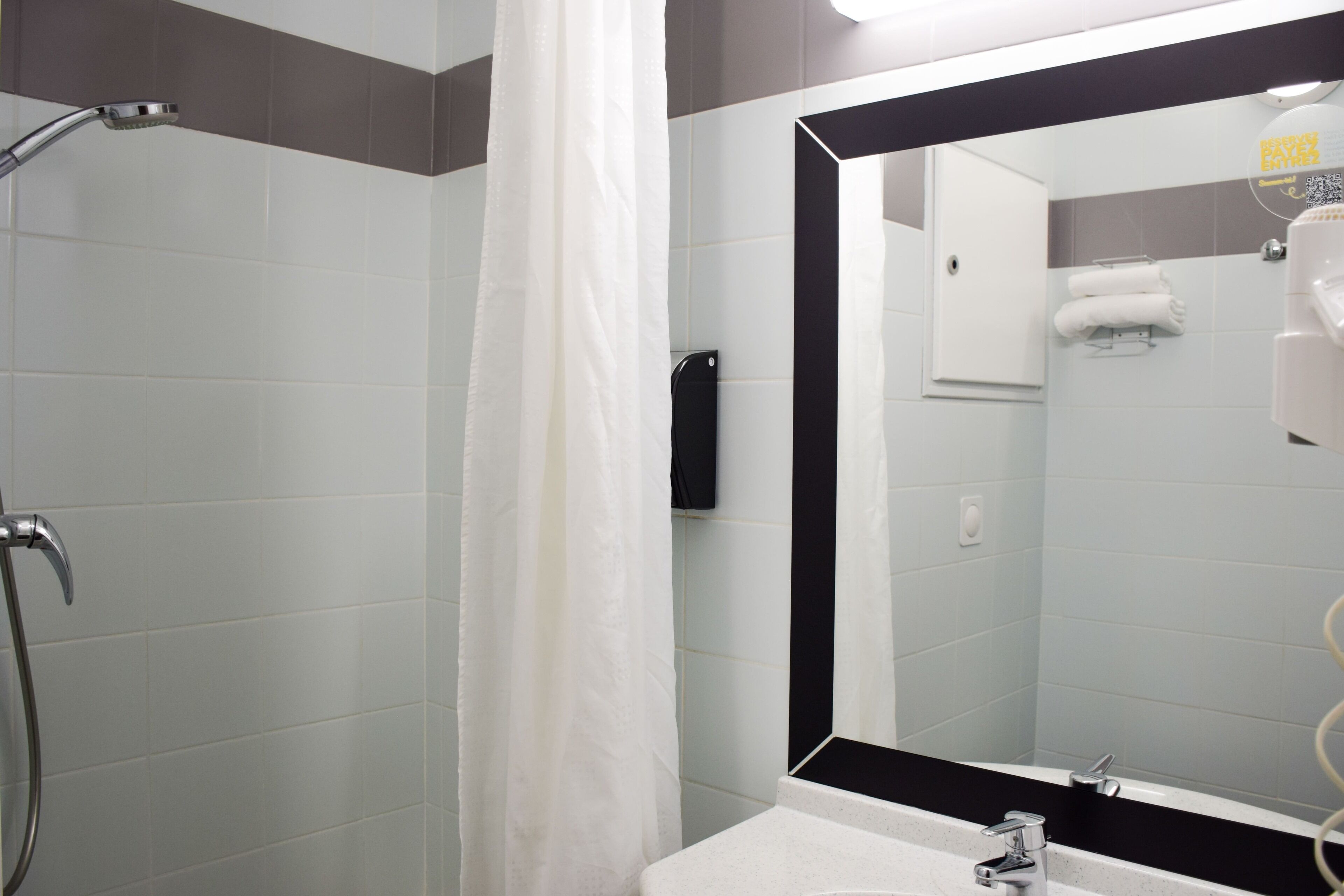 Une salle de bain avec une douche, un lavabo et un miroir.