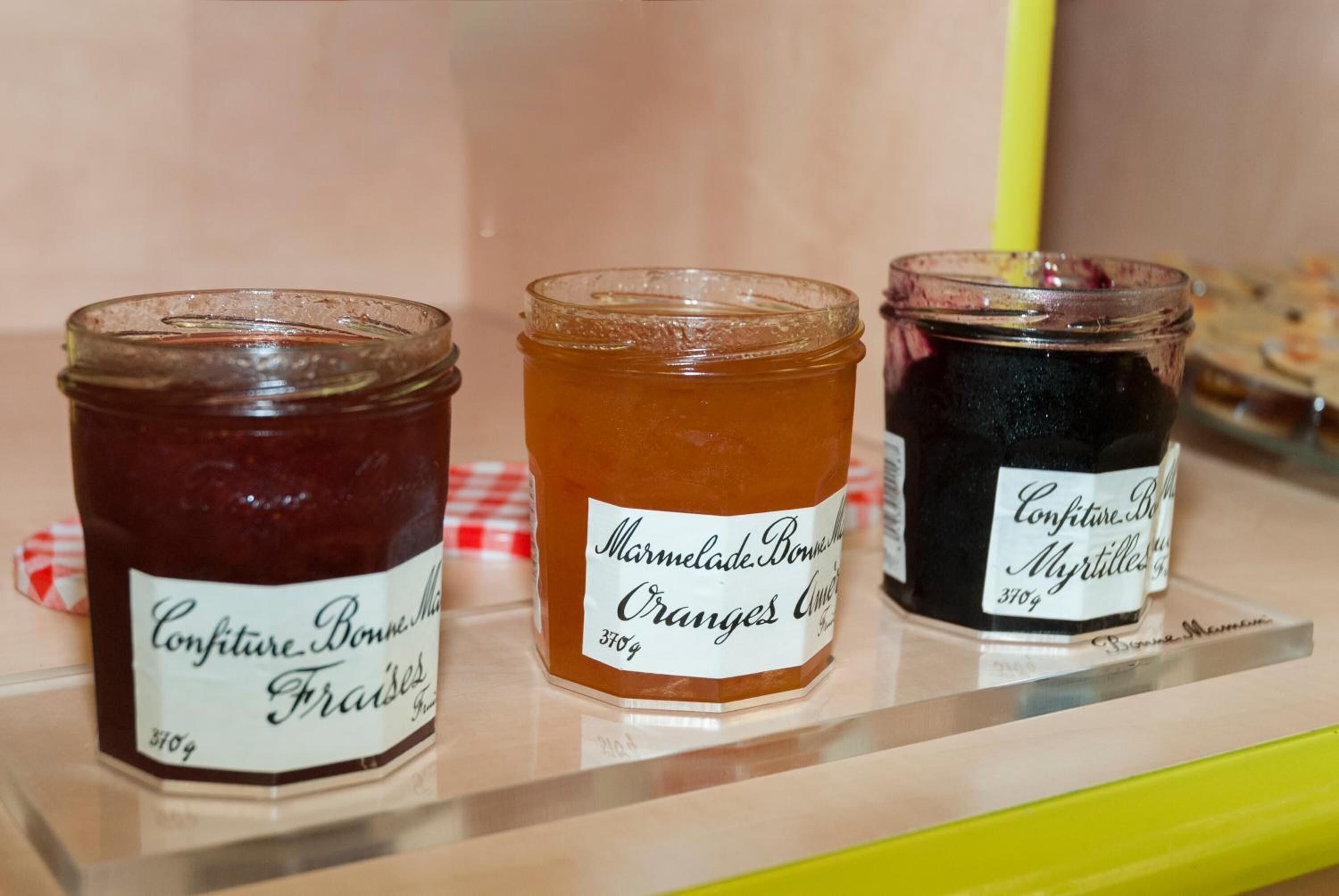 Three jars of marmalade on a shelf.