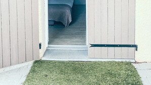 Una puerta que da a un dormitorio con una cama, una mesita de noche y una lámpara de pared.