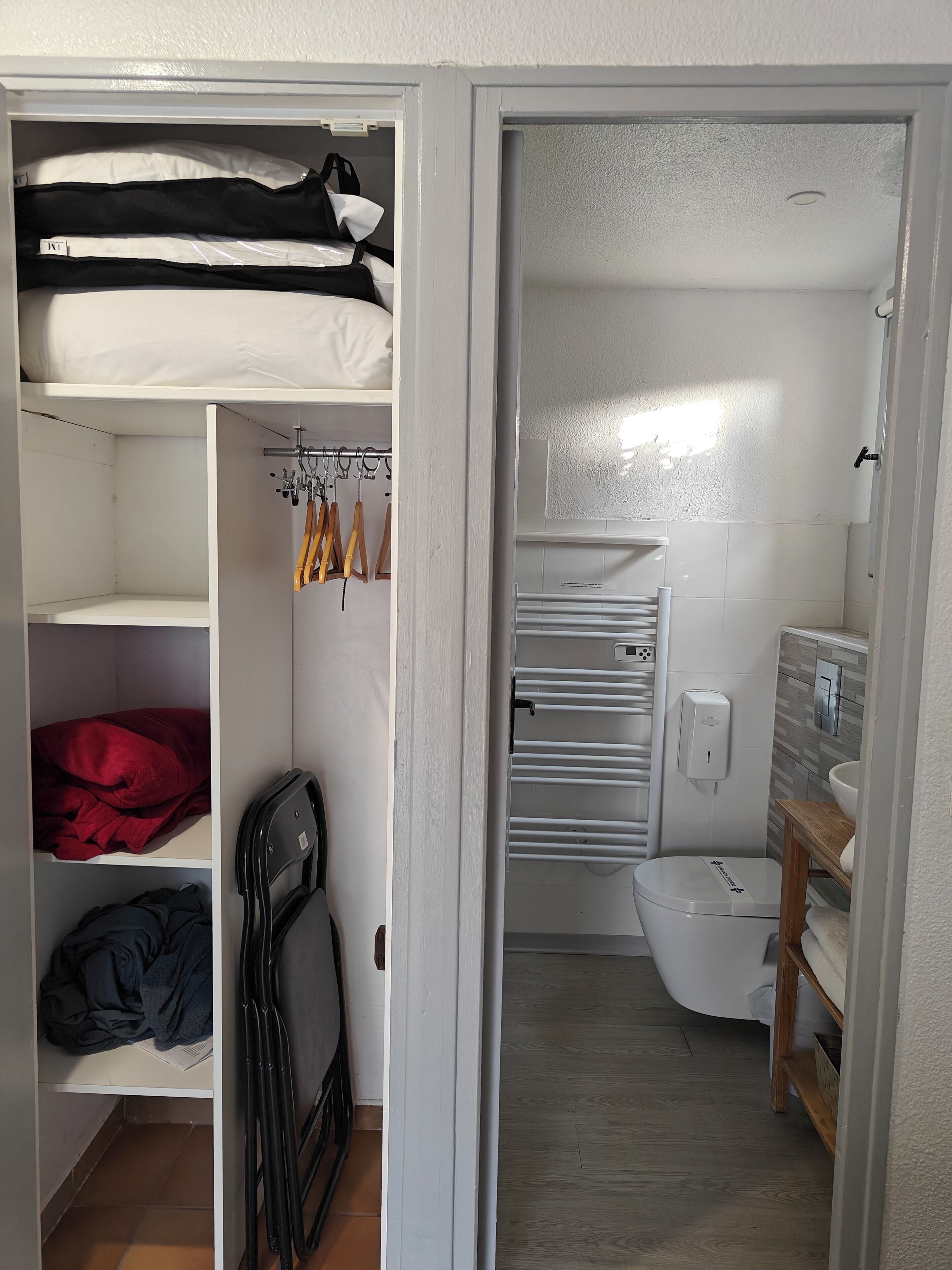 A compact room with a bunk bed, a small seating area, and a bathroom with a toilet and sink.