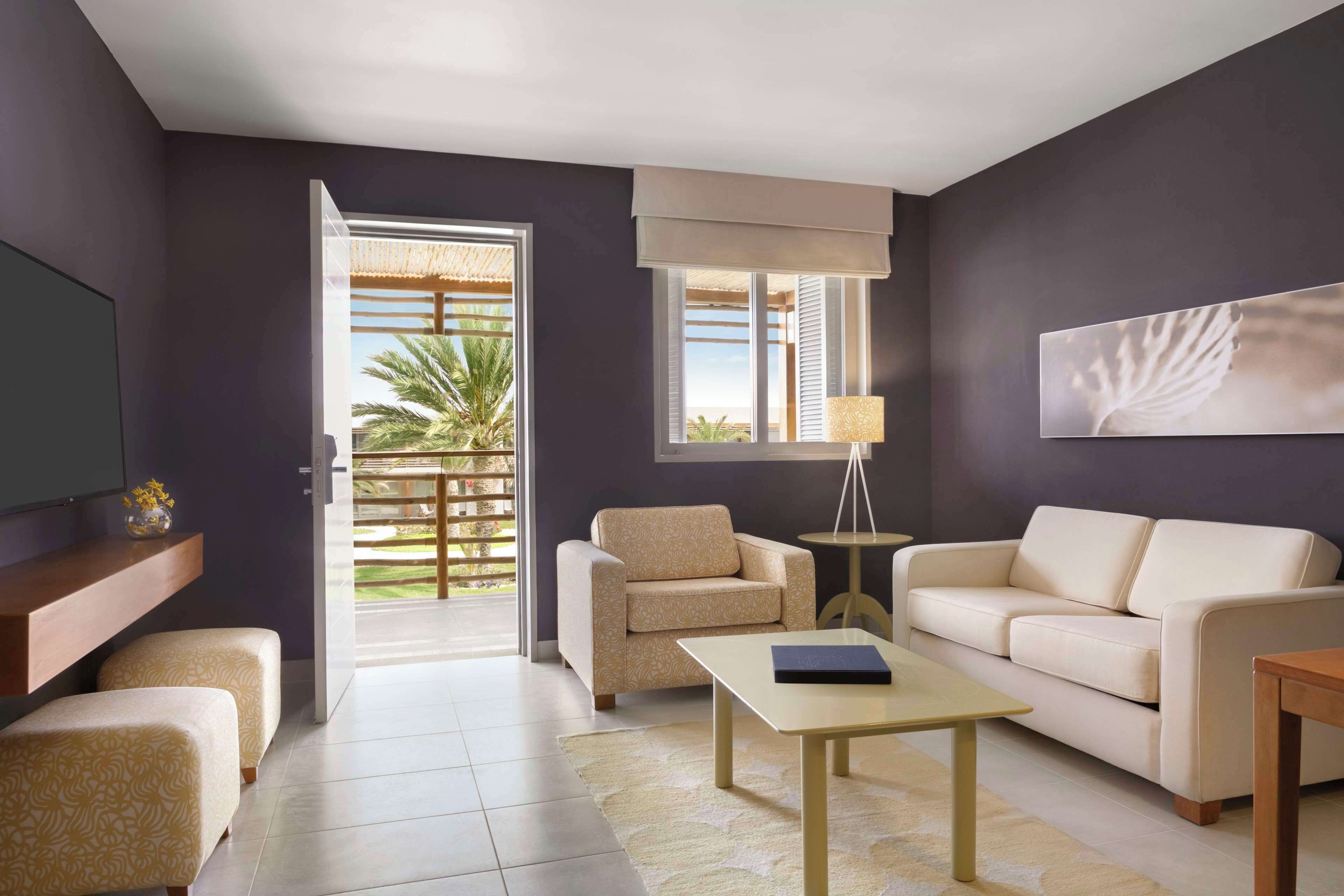 A modern living room with a sofa, armchair, coffee table, and a TV on a stand.