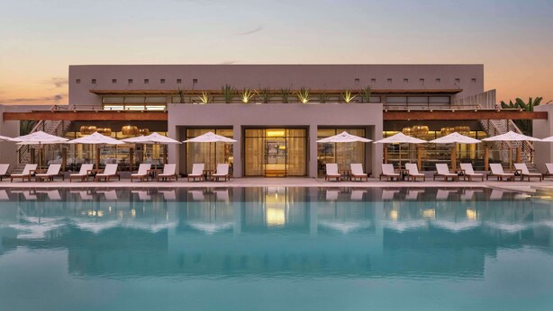 Ein modernes Hotel mit Pool, Liegestühlen und Sonnenschirmen.