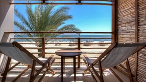 Ein Balkon mit Blick auf den Strand, zwei Hängematten und ein kleiner Tisch.