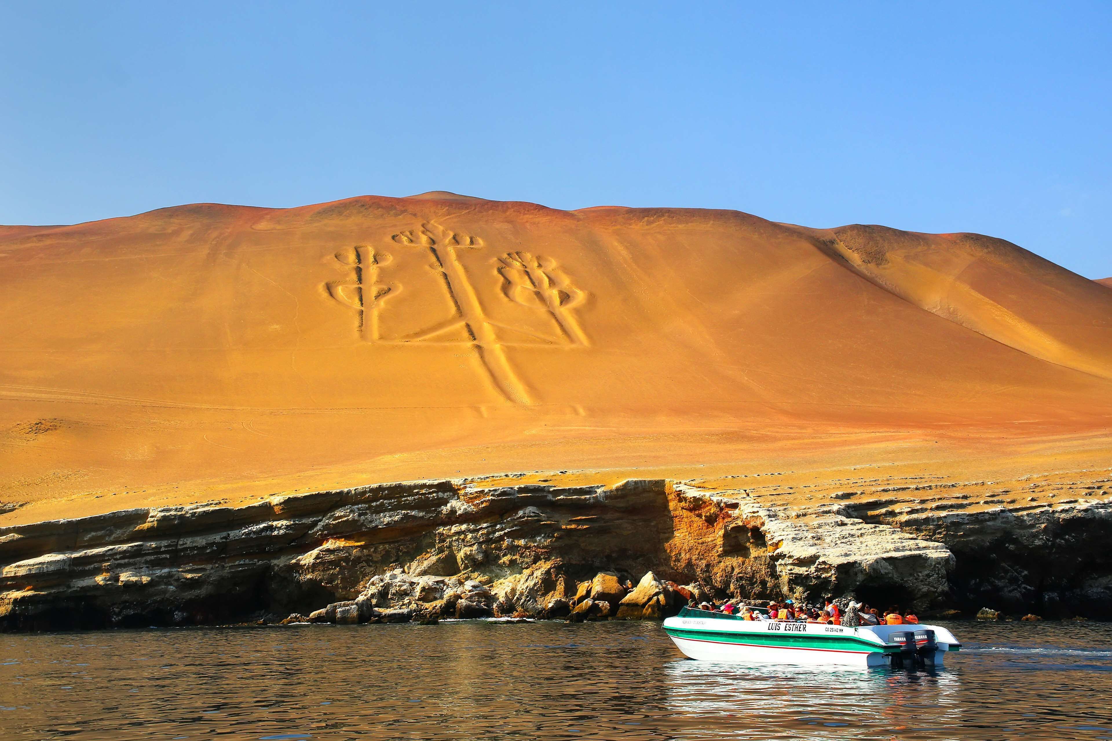 A boat with 'LUS ESTHER' written on it, a desert landscape with sand dunes, and a rocky shoreline.