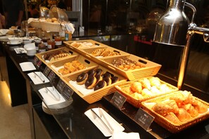 Un bufé con diversas opciones de comida, incluyendo pasteles y donas.