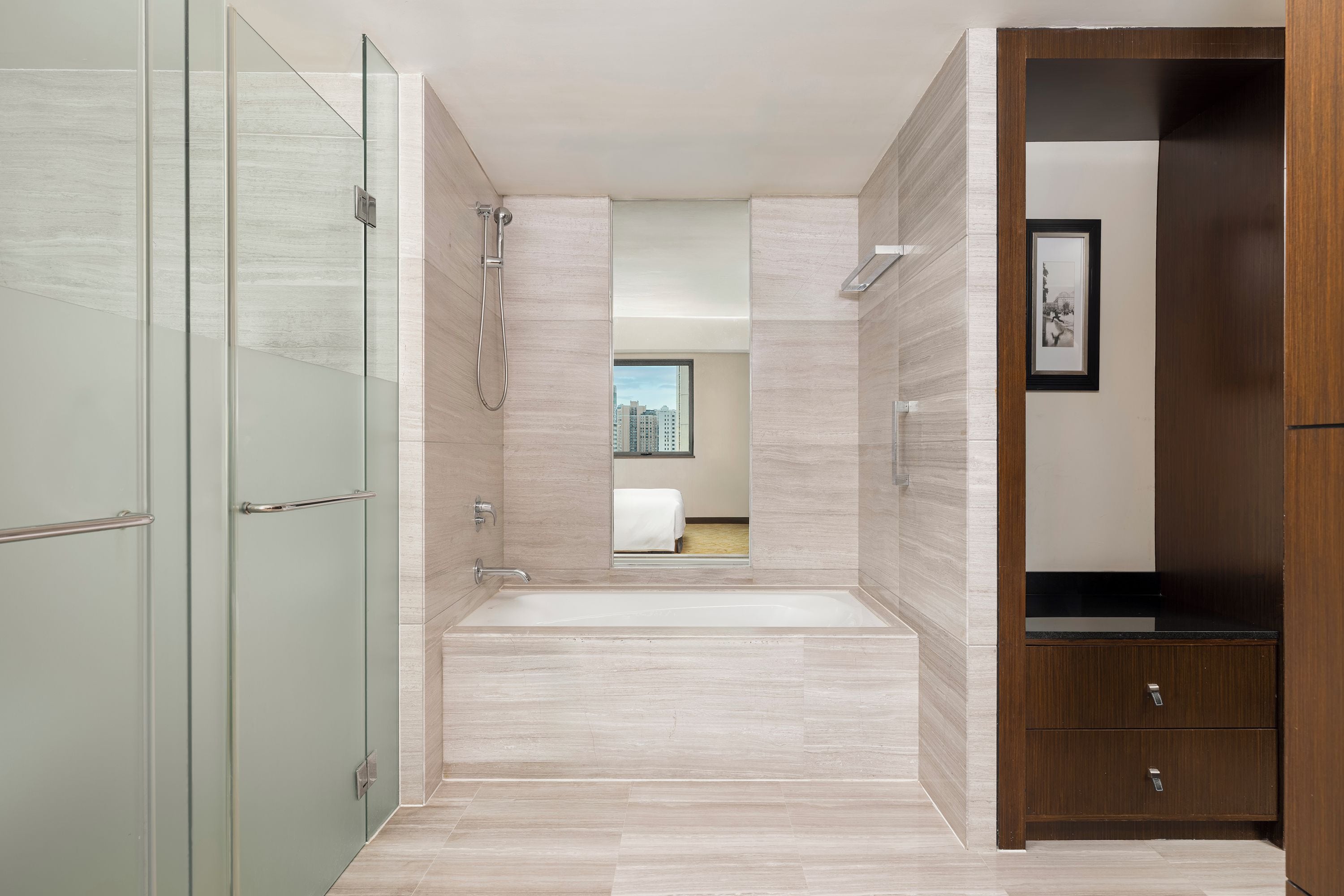 A modern bathroom with a glass shower enclosure, a freestanding bathtub, and a wooden vanity with a black countertop.