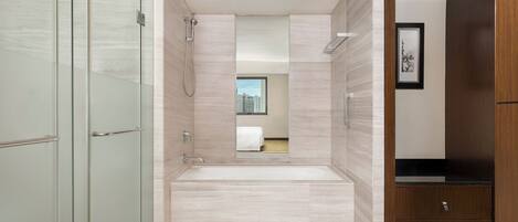 A modern bathroom with a glass shower enclosure, a freestanding bathtub, and a wooden vanity with a black countertop.