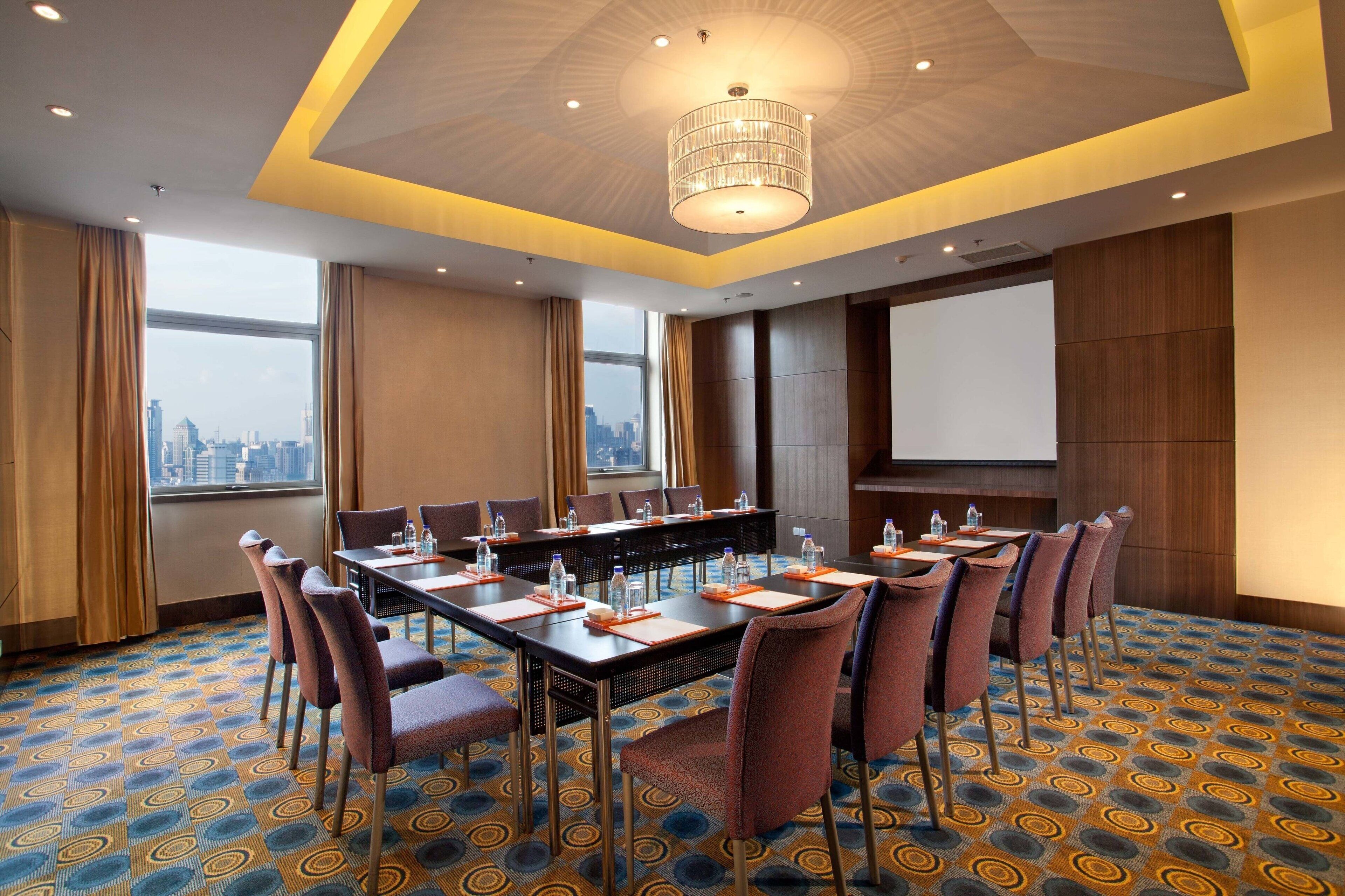 A conference room with a city view, a large table with chairs, and a projector screen.