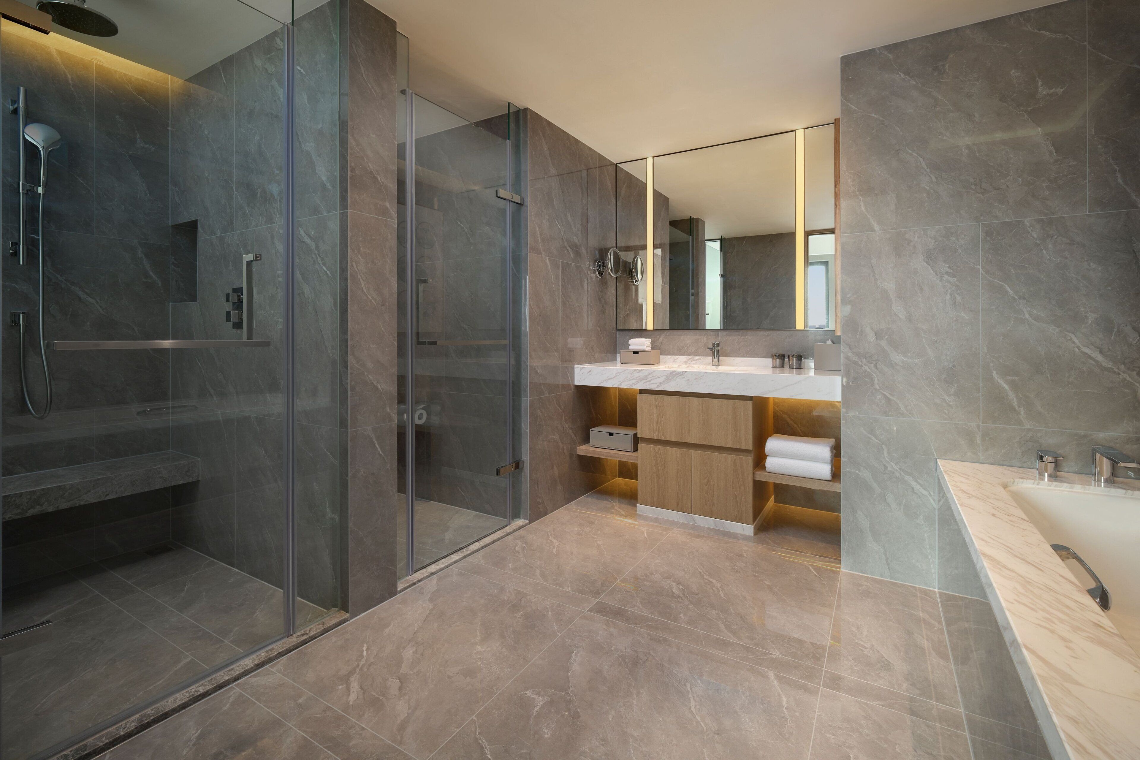 Une salle de bain moderne avec une douche à parois de verre, un grand miroir et un sol carrelé en marbre.