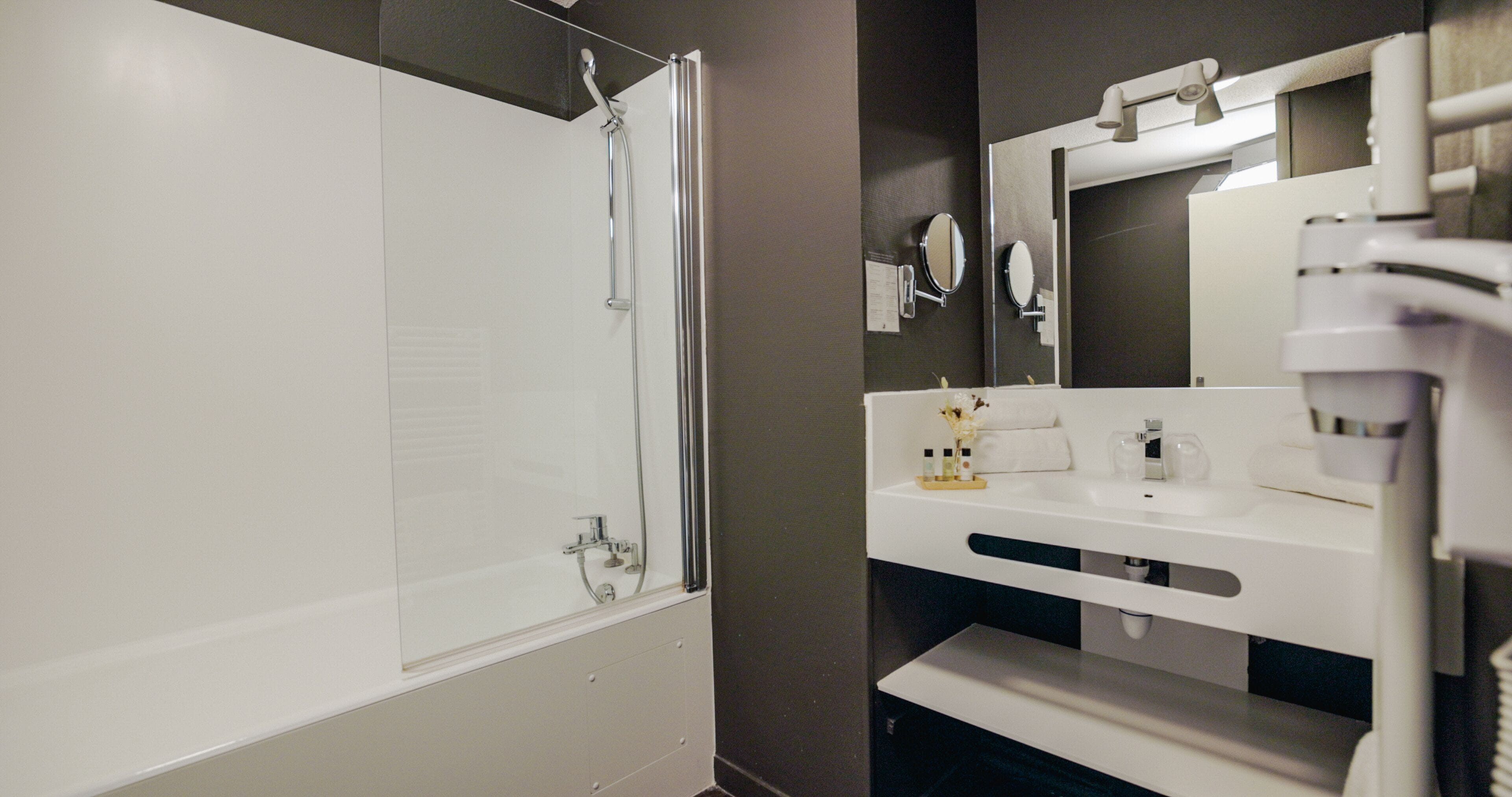 A modern bathroom with a bathtub, a sink with a mirror, and a shower.