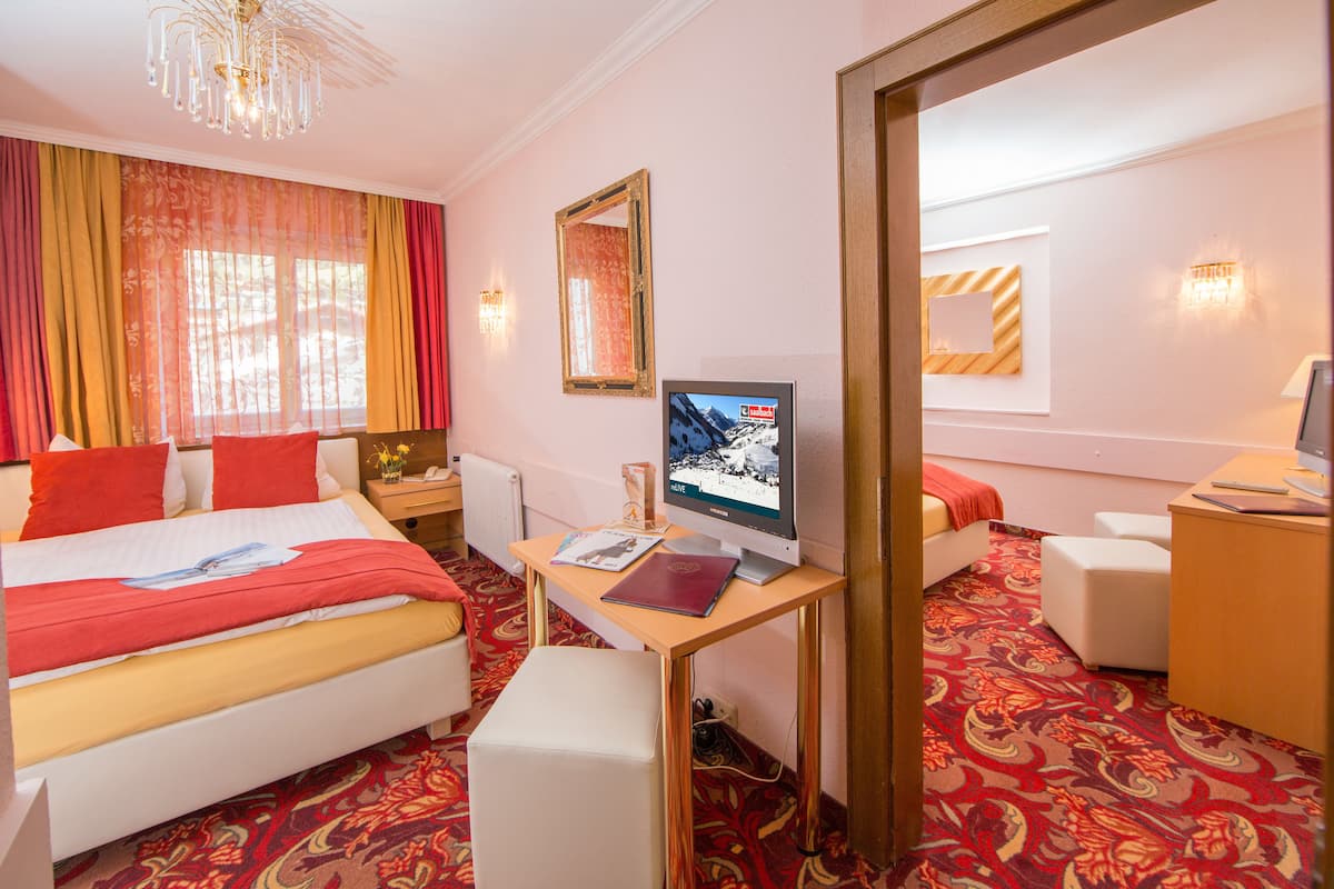 Ein Hotelzimmer mit einem Bett, einem Schreibtisch mit Computer, einem Sessel und einem großen Spiegel.