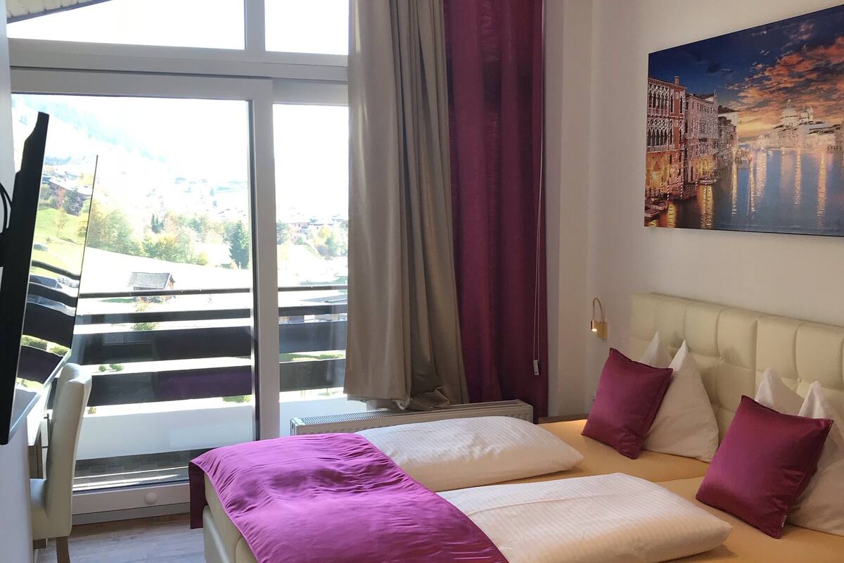 Ein Hotelzimmer mit einem großen Bett, einem Schreibtisch, einem Stuhl und einem Bild an der Wand.