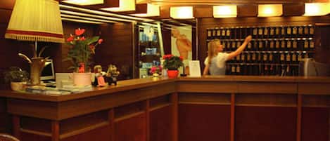 Zona de bar con mostradores de madera, una variedad de botellas y una mujer de pie detrás.