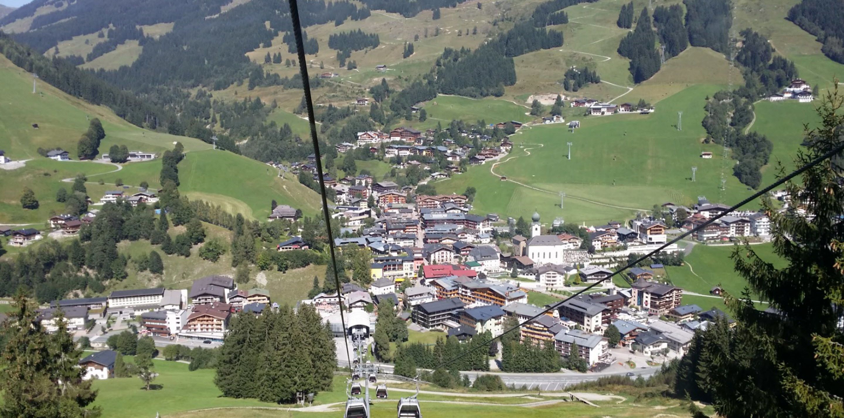 A mountainous town with traditional buildings, a ski lift, and a winding road.