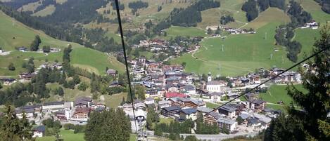 A mountainous town with traditional buildings, a ski lift, and a winding road.