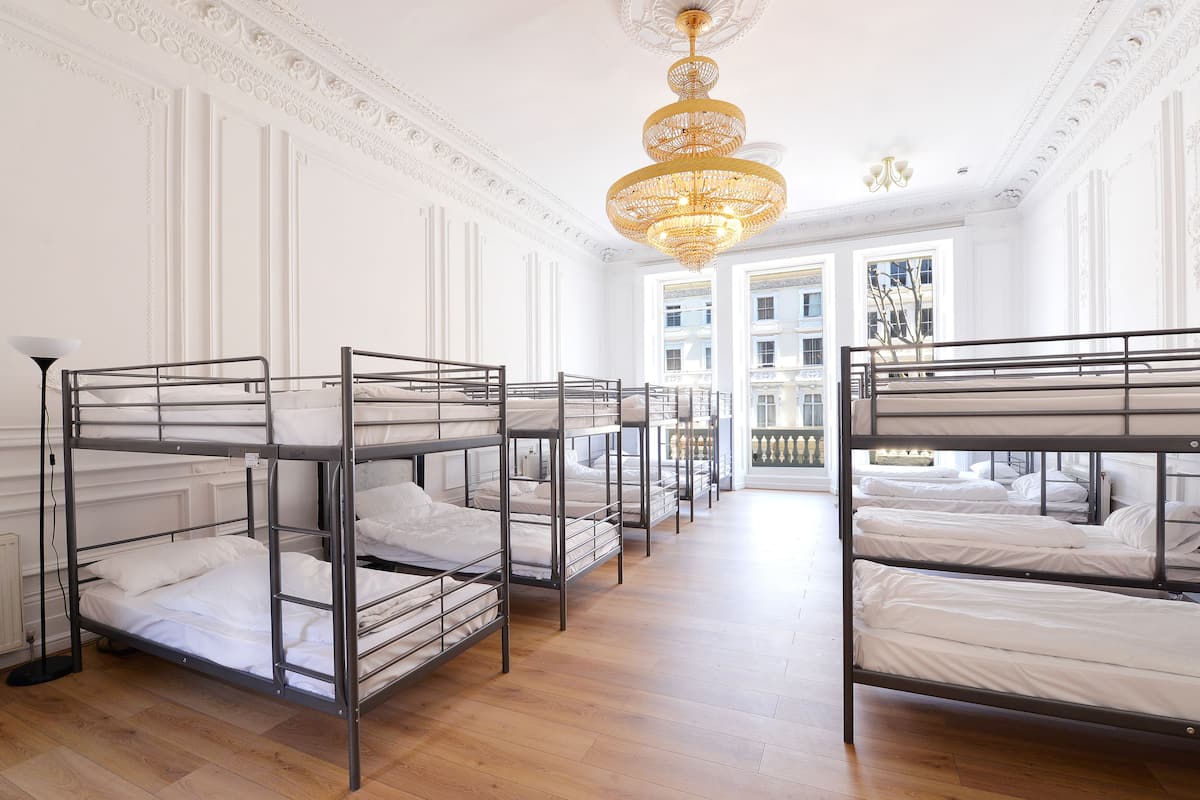 A hotel room with bunk beds, a chandelier, and a view of the city through large windows.
