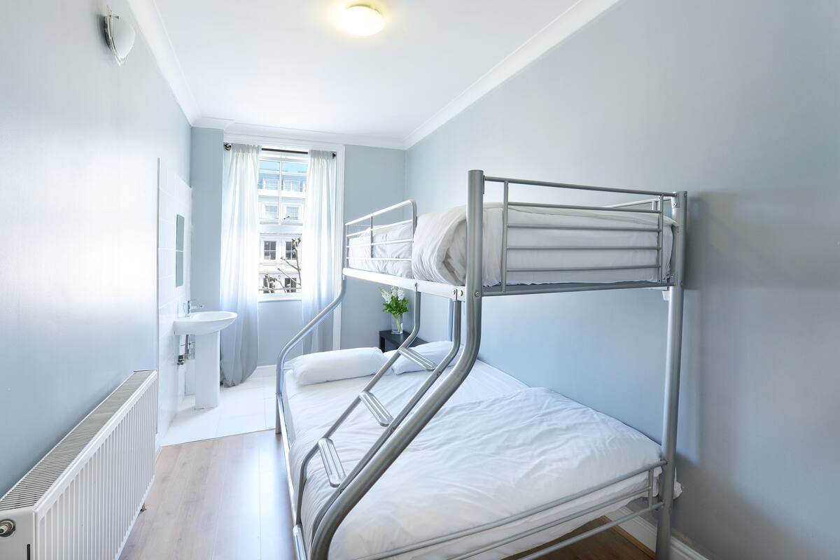 A bunk bed room with a window, a sink, and a radiator.