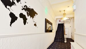 Un pasillo con un mural de mapa mundial, una escalera con alfombra estampada y un cuadro en la pared.